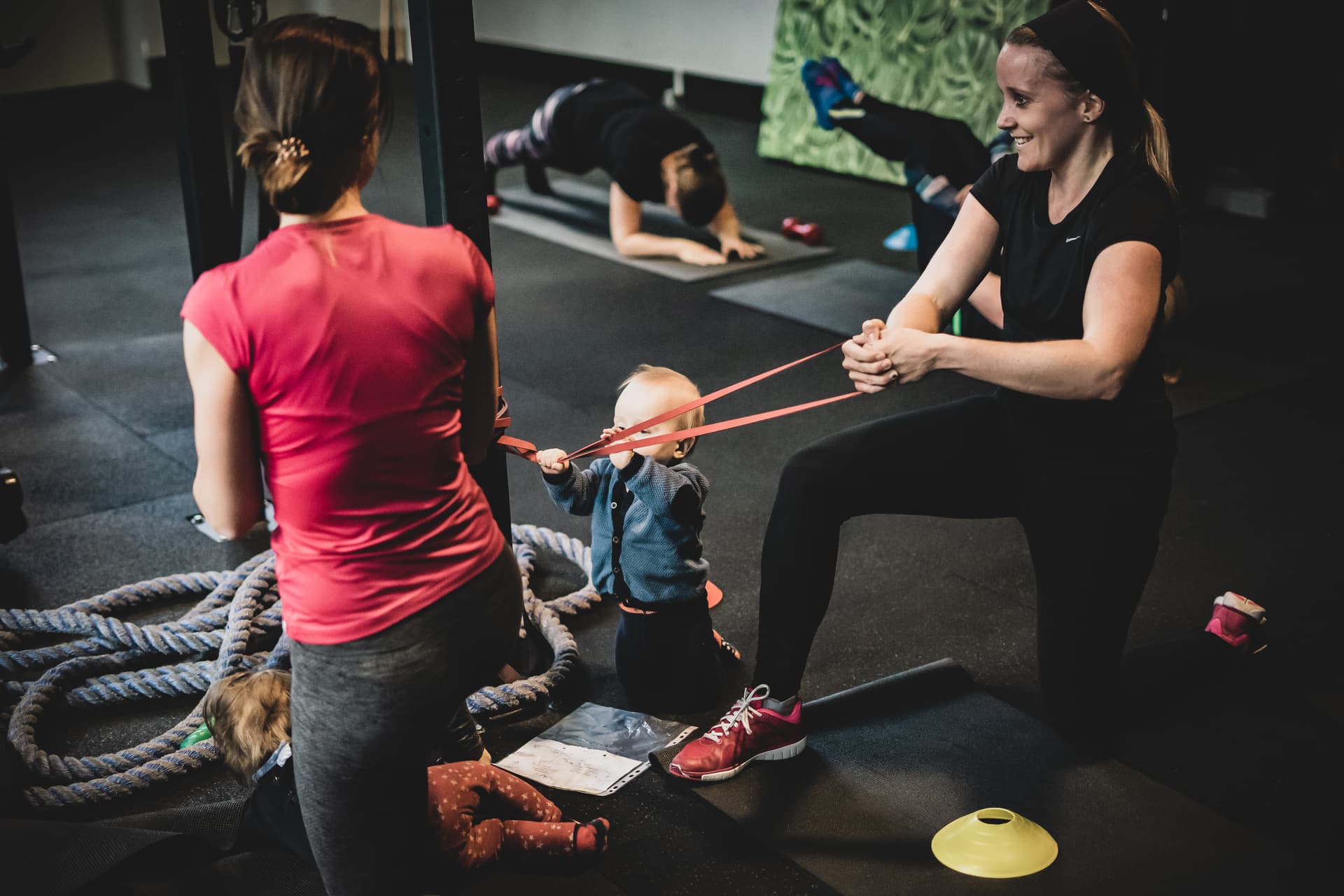 Fitte Mama bei Kniebeugen mit Baby im Arm.