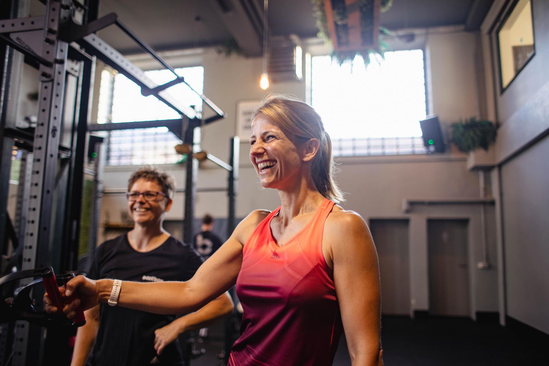 Kundin lacht am Slingtrainer beim Personal Training in der Bootbox Köln.