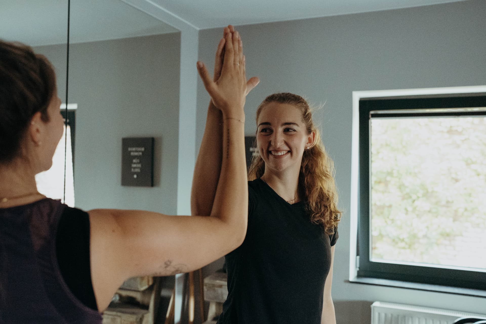Lächelnde Trainerin mit Kundin beim Dehnen