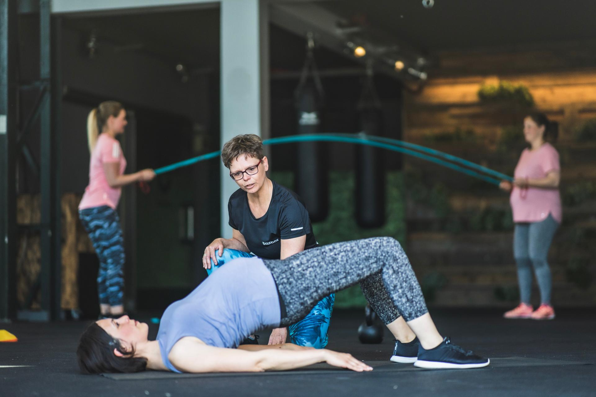 Fitnesstrainerin korrigiert Gluten Bridge bei Teilnehmerin Fit Mum Kurs der Bootbox Köln Ehrenfeld