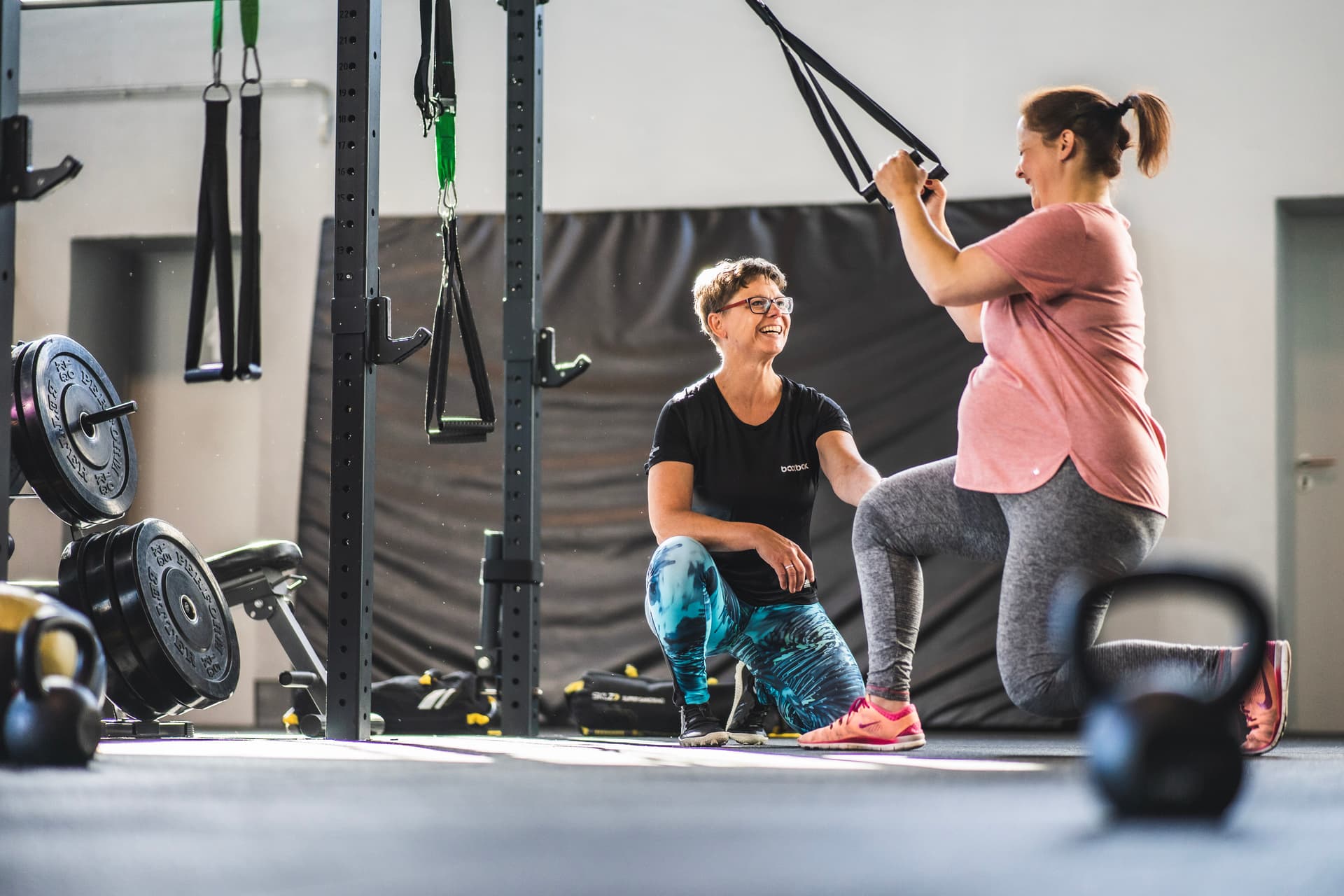 Trainerin Nadine Schmitz korrigiert Teilnehmerin des Schwangerenkurses am Slingtrainer