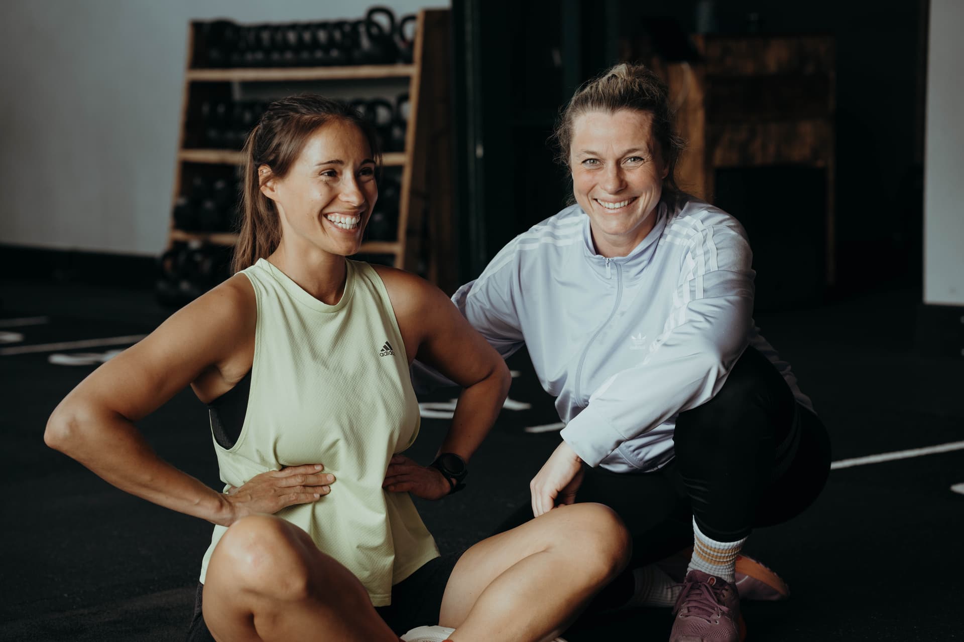 Eine Schwangere des Schwangerenkurses der Bootbox sitzt mit Personal Trainerin Saskia am Boden und hält ihre Hände auf dem Bauch